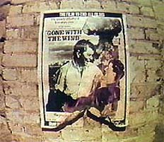 Film frame from 'AMERIKA' by Al Razutis - Poster of Ronald Reagan and Margaret Thatcher burning on wall